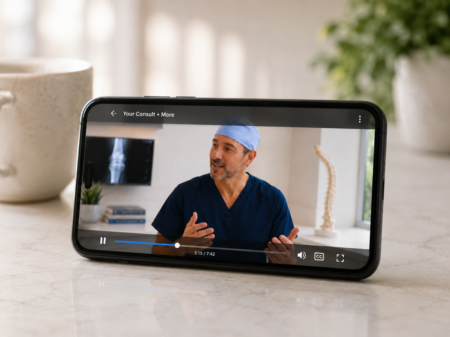 A phone on a kitchen counter playing a video from the surgeon